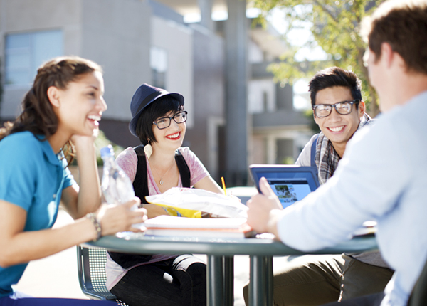 A group of college students sit at a table, representing the concept of community college insurance. 
